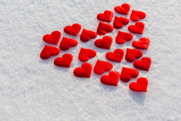 Many red hearts in a shape of big heart on glittering snow. Vilentine's day theme.