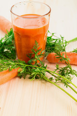 Fresh carrot juice in glass on wooden table background.