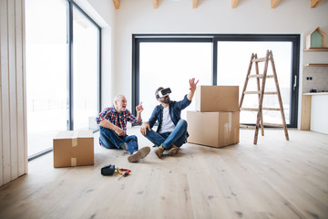 A man with VR goggles and his senior father furnishing new house, a new home concept.