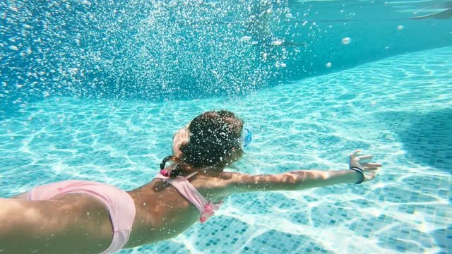 Little girl wearing snorkeling mask swimming underwater in the pool. Slow motion