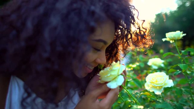 Young attractive ethnic woman smelling the flowers in the garden