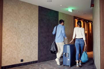 Couple arriving at hotel lobby with suitcase.
