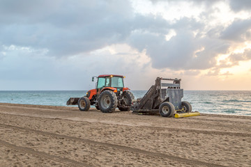 Obraz premium preparing the beach early morning with a tractor and a roller