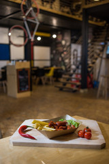 Sausages and french fries on a wooden board with fresh vegetables.