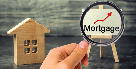 Wooden house and the inscription Mortgage and up arrow. Raising mortgage rates and tax. The...