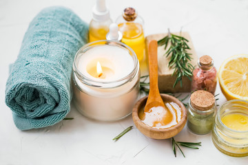 Spa products with candle, towels, manuka honey, oils, clay, bath salt, salve balm, spa setting with...
