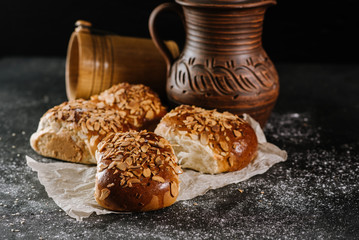 Fresh baked sweet buns with jar and fabric on the black wooden background