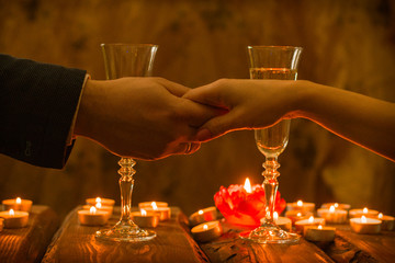 A man and a woman at a romantic dinner. The hand of a man and a woman reach for each other by candlelight.