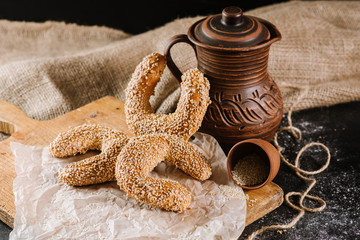 Fresh baked sweet buns with jar and fabric on the black wooden background