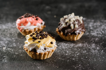 Fresh sweet cupcakes on the black wooden background