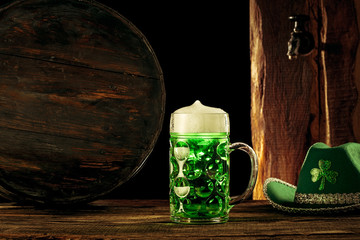The wooden barrel background with lots of gold coins and a large mug of beer with a green bow. Background for St. Patrick's Day celebration and religious holiday concept