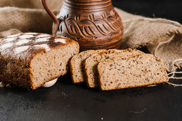 Fresh baked bread with jar and fabric on the black wooden background