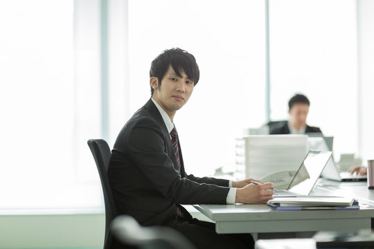 オフィスデスクに座る日本人ビジネスマン