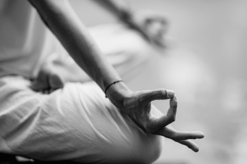 Close up image of woman’s hands in lotus position by the lake