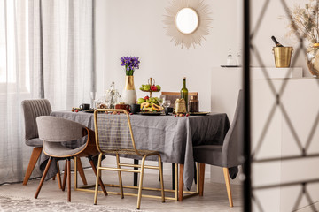 Dining room table covered with grey tablecloth in bright interior