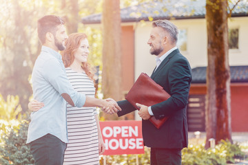 Real estate agent congratulating smiling couple buying home