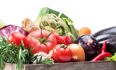 Fresh multi-colored vegetables in wooden crate.
