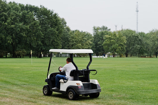 Man driving golf car on the golf course.