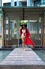 beautiful gorgeous brunette girl with flowing hair in a white bathing suit and a red tunic goes to the pool