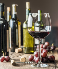 Glass of red wine on the table. Wine bottle and grapes at the background. © volff