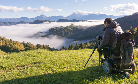man on wheelchair taking photos of beautiful landscape in a foggy morning, St. Thomas Slovenia