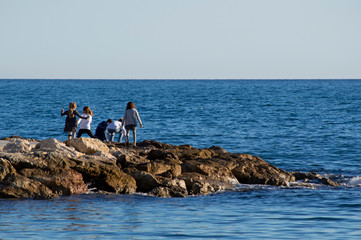 Fototapeta na wymiar Niños jugando en el espigón / Children playing on the breakwater. Málaga