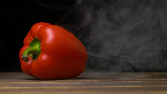 farm ripe capsicum or sweet pepper is on the table and smoke blows from behind, cloese up 4K, copy space