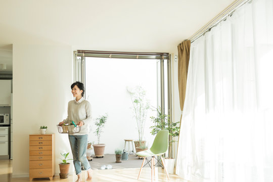 鉢植えを持って部屋に入る女性