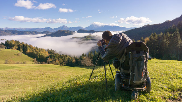 man on wheelchair taking photos of beautiful landscape in a foggy morning, St. Thomas Slovenia