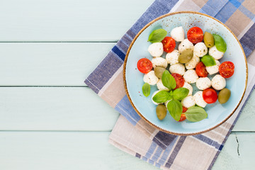 Delicious caprese salad with ripe cherry tomatoes and mini mozzarella cheese balls with fresh basil leaves.