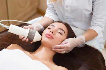 The procedure of photoepilation in the beauty salon. A young woman is removed unwanted hair on her face. Hardware cosmetology. Microcurrent therapy. Close up