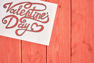 Sheet of paper with beautiful inscriptions "Valentines day" lie on a textured wooden substrate " living coral" color