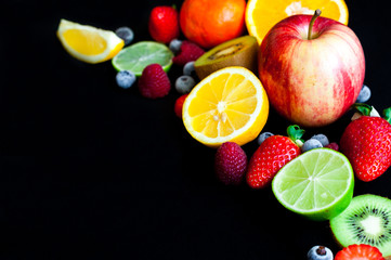 close up of background with spring and summer vivid colorful fruits on blakc table with wide copy space