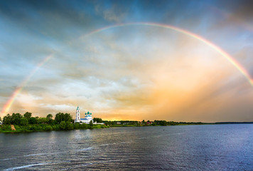 Naklejka na ściany i meble Beautiful church on the river bank and rainbow after rain