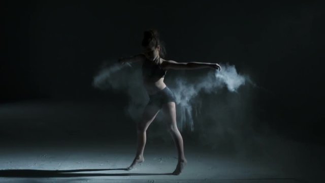 Caucasian girl wearing black leotard performing edgy contemporary dance moves