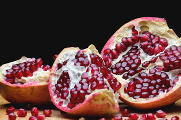 Ripe red fruit pomegranate with seeds on black  background, close-up photo 