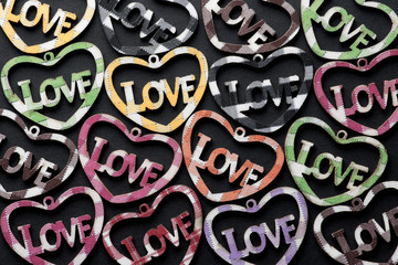  Multicolored hearts with the inscription LOVE, on a black background, flat lay.Valentine's day holiday concept.