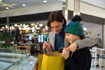 Mother looking in shopping bag with her daughter - Image