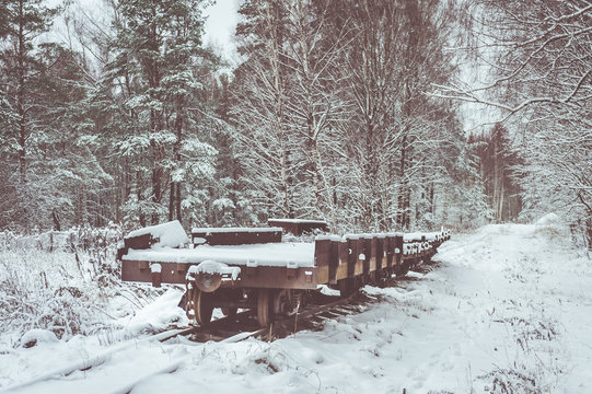 Narrow gauge railway leading through a forest.  Authentic soviet time train covered with snow. Train at rail track. Toned image.