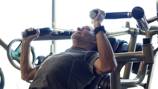 A senior man doing strength workout exercise in gym. Slow motion.