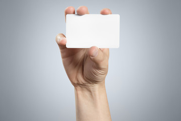 Obraz premium Hand holding a blank card or a ticket/flyer on gray background