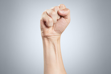 Raised up aggressive fist on gray background