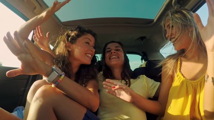 Three female friends enjoying traveling in the car. Sitting in rear seat and having fun on a road trip. - Powered by Adobe