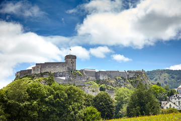 Chateau Fort of Lourdes. Castle on a rock. Blue sky with white clouds. French city is located in southern France in the foothills of the Pyrenees mountains