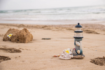 Beautiful decor in the form of a lighthouse and seashells on the sand with space for the text