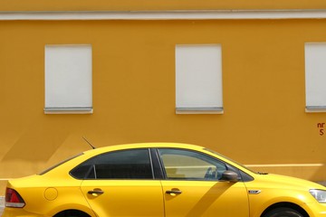 taxi car yellow wall parked car parking parking tinted windows headlights closed sun street city moscow russia private vehicles