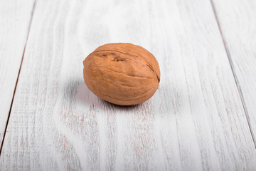 One whole walnut on wooden background, healthy brain food, walnut on light vintage table