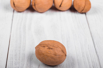 whole walnut on wooden background, the background of a pile of walnut in the blur, light walnut vintage table.