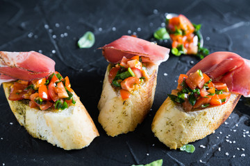 Bruschetta with prosciutto, tomatoes and basil