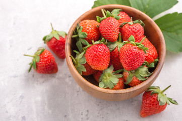 A bowl of beautiful and delicious strawberries isolated on a architectural concrete background, closeup, topview, copyspace.